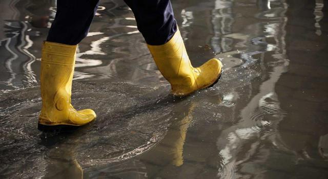 La C.Valenciana beneficia empresas que han solicitado ERTEs por fuerza mayor. Imagen de individuo con botas de agua andando sobre suelo mojado