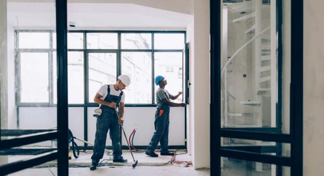 Las obras de transformación de un local que se ha dejado de arrendar a efectos del IS. Dos trabajadores de la construcción trabajando juntos en una obra