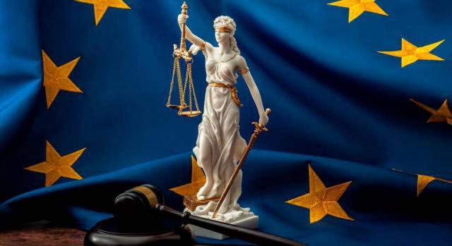 Desde el 1 de octubre de 2024 empiezan a aplicarse las normas relativas a la transferencia parcial de la competencia prejudicial del Tribunal de Justicia al Tribunal General. Imagen de un mazo, de la diosa de la justicia con su balanza sobre una bandera de la UE